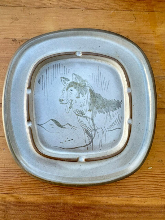 Decorative ashtray with a dog design on a wooden surface