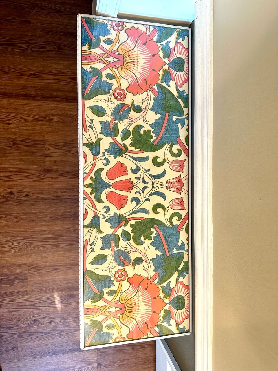 Decorative floral patterned table with a wooden floor and beige wall background