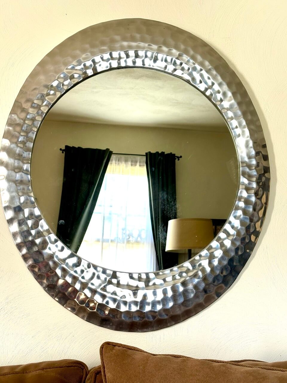 Round decorative mirror with a textured frame on a wall.