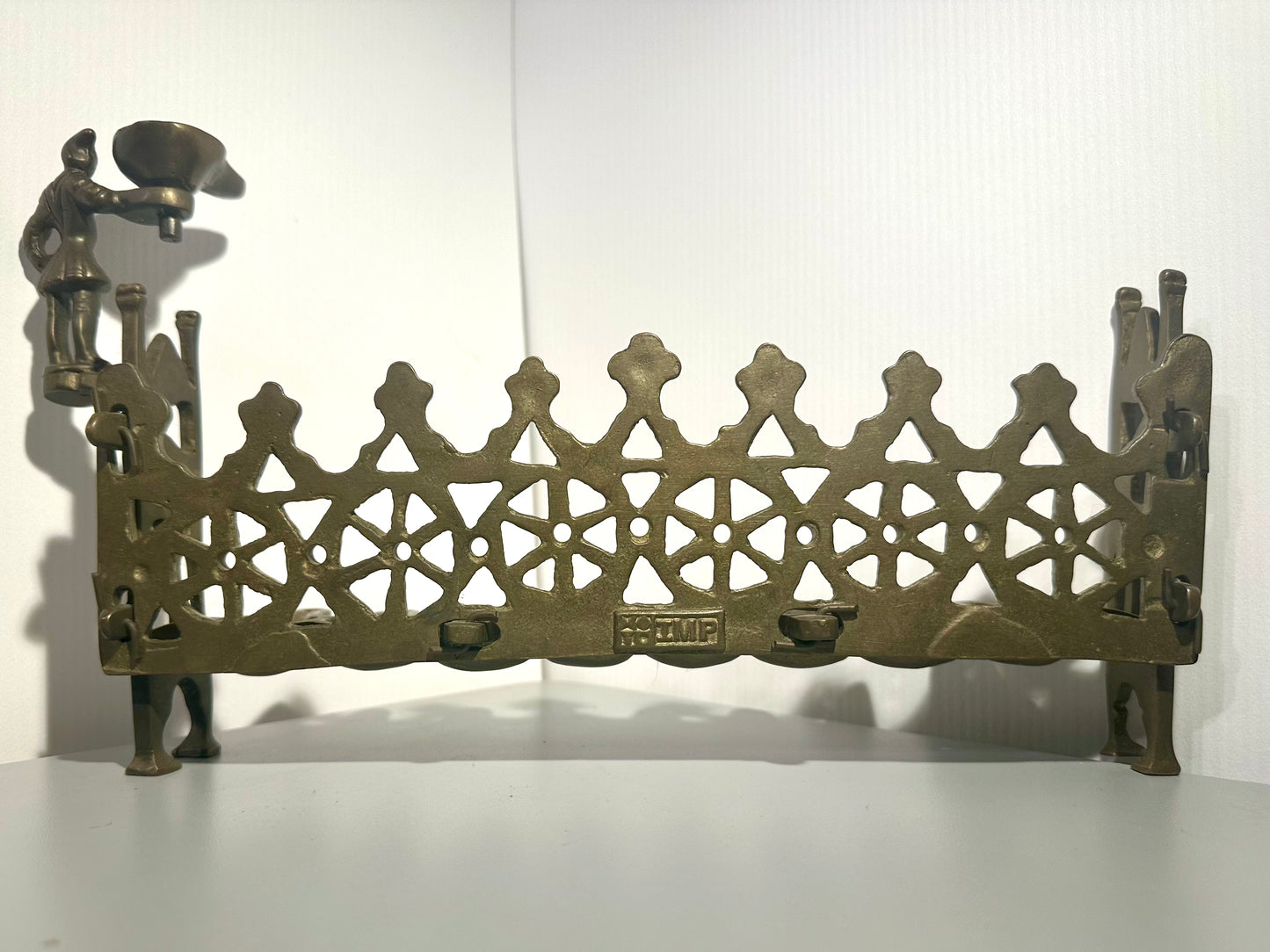 Decorative metal Hanukkah Oil Lamp with intricate design and figures on a white background