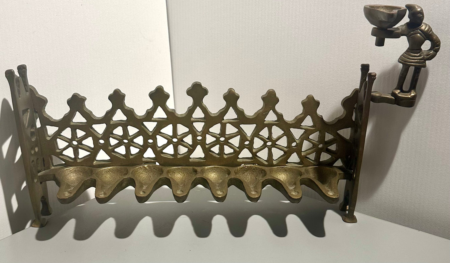 Brass Hanukkah oil Lamp with  decorative design and small figure on a white background