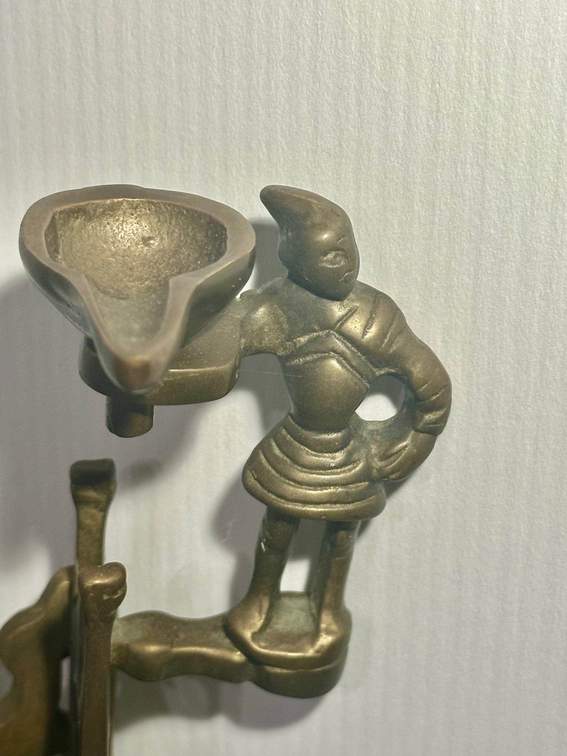 Bronze sculpture of a figure with a bowl on a white background