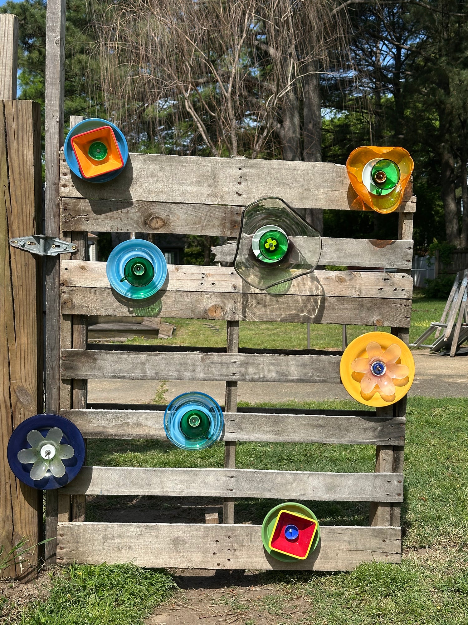 Wooden pallet with colorful glass yard art on a grassy outdoor setting