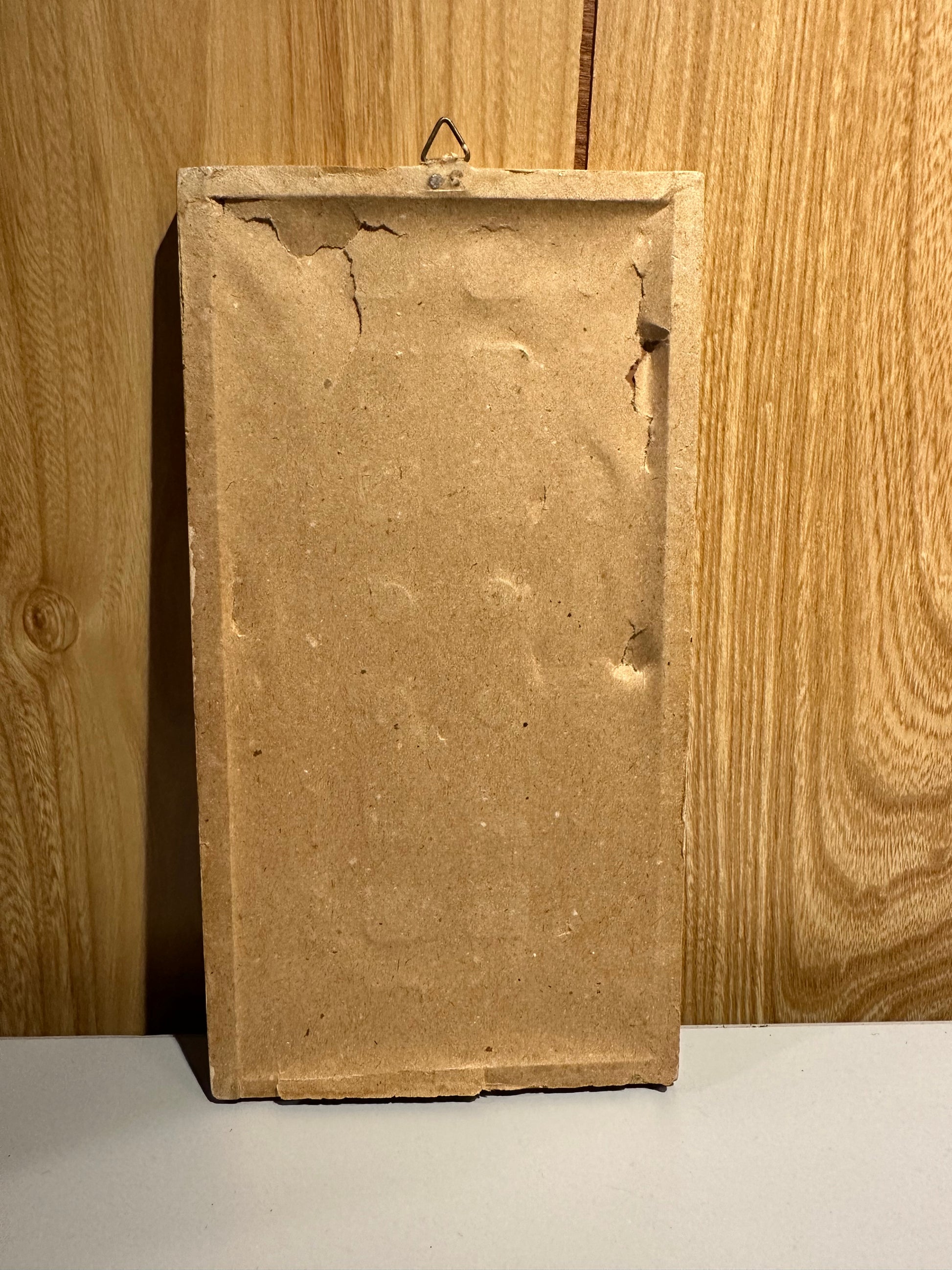 Rectangular back view of a dust cover on framed art against a wooden surface