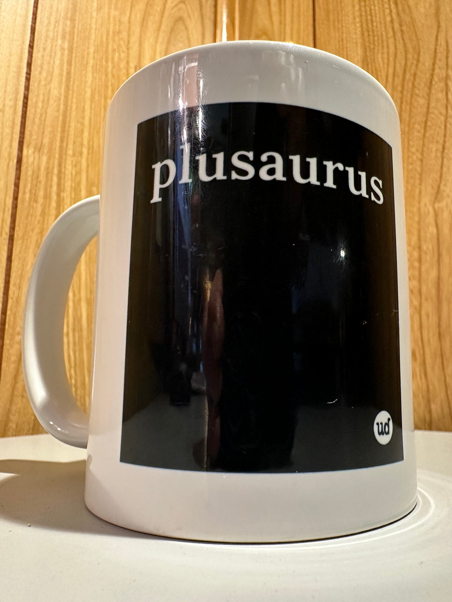 Mug with 'plusaurus' text on a wooden surface