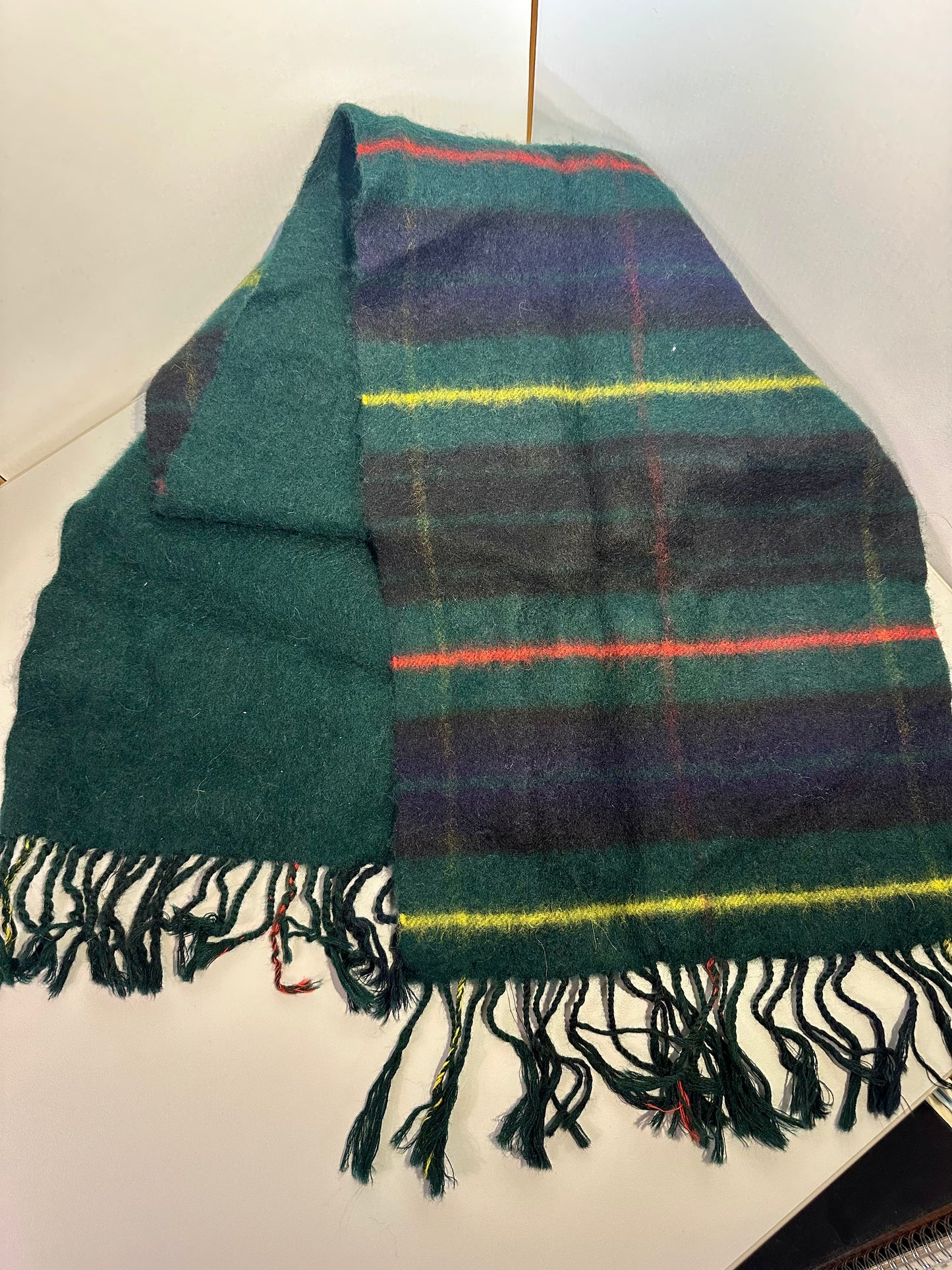 Green plaid scarf with colorful stripes on a white background