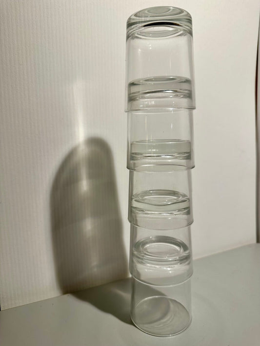 Stack of clear glass glasses on a white surface with a white background