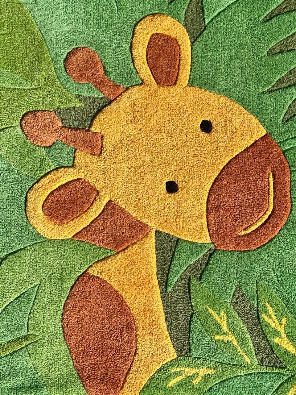 Children's rug with a cartoon giraffe design on a green leafy background