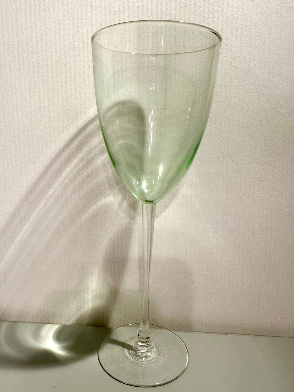 Green wine glass on a textured white background