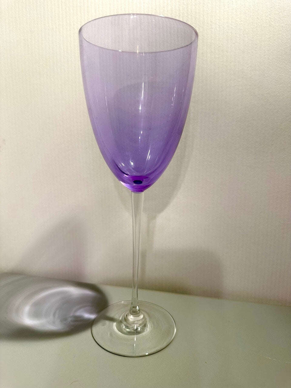 Purple wine glass on a white surface with a plain background