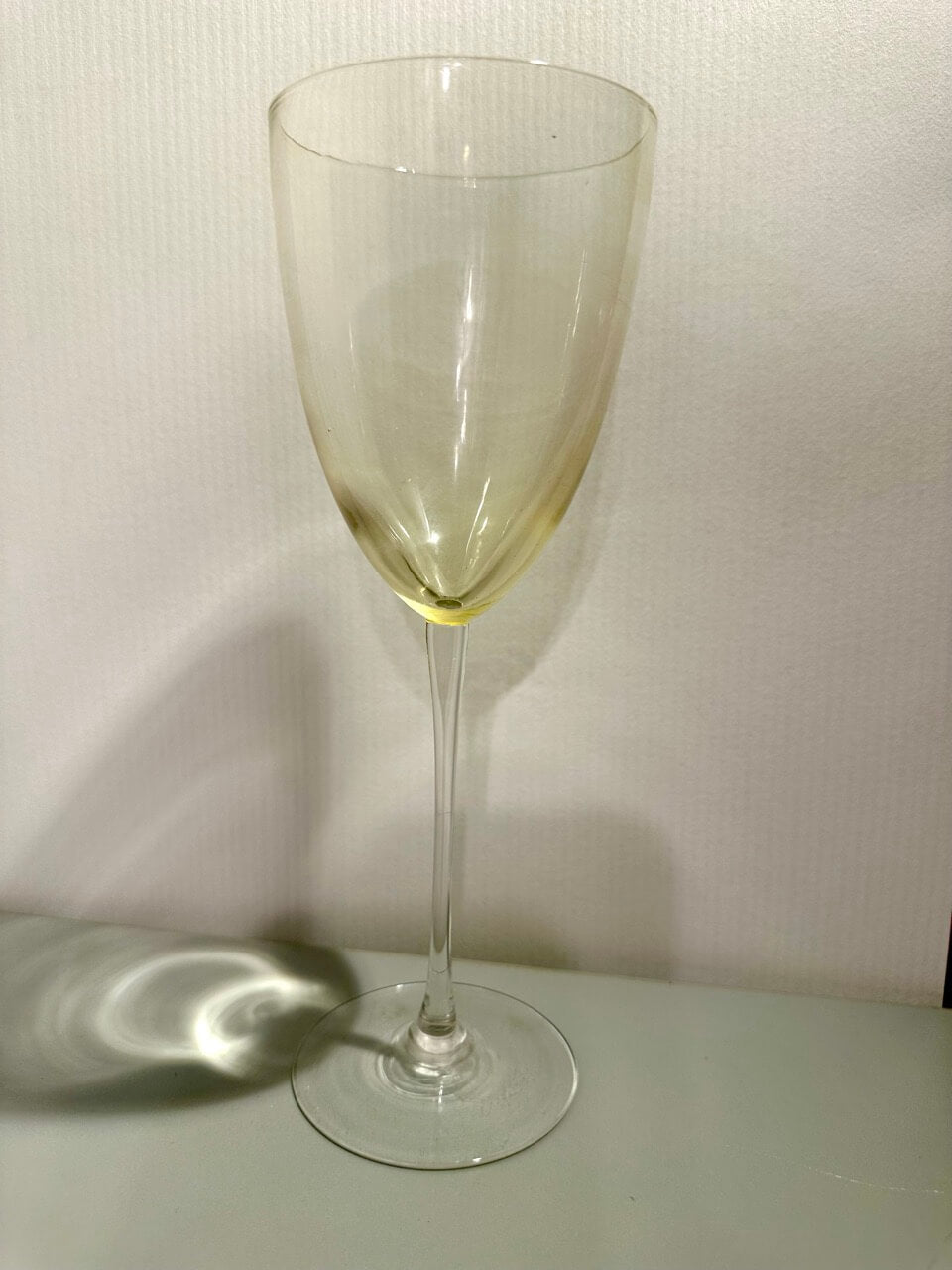 Clear wine glass on a white surface with a white background