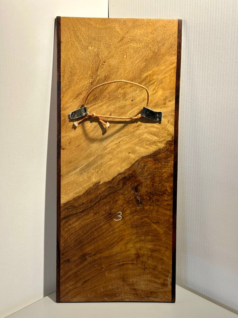 Wooden board with a picture wire on a plain background