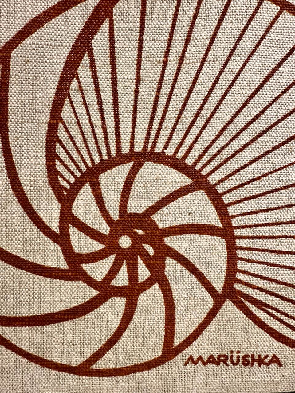Brown spiral design on beige fabric with 'Marushka' branding.
