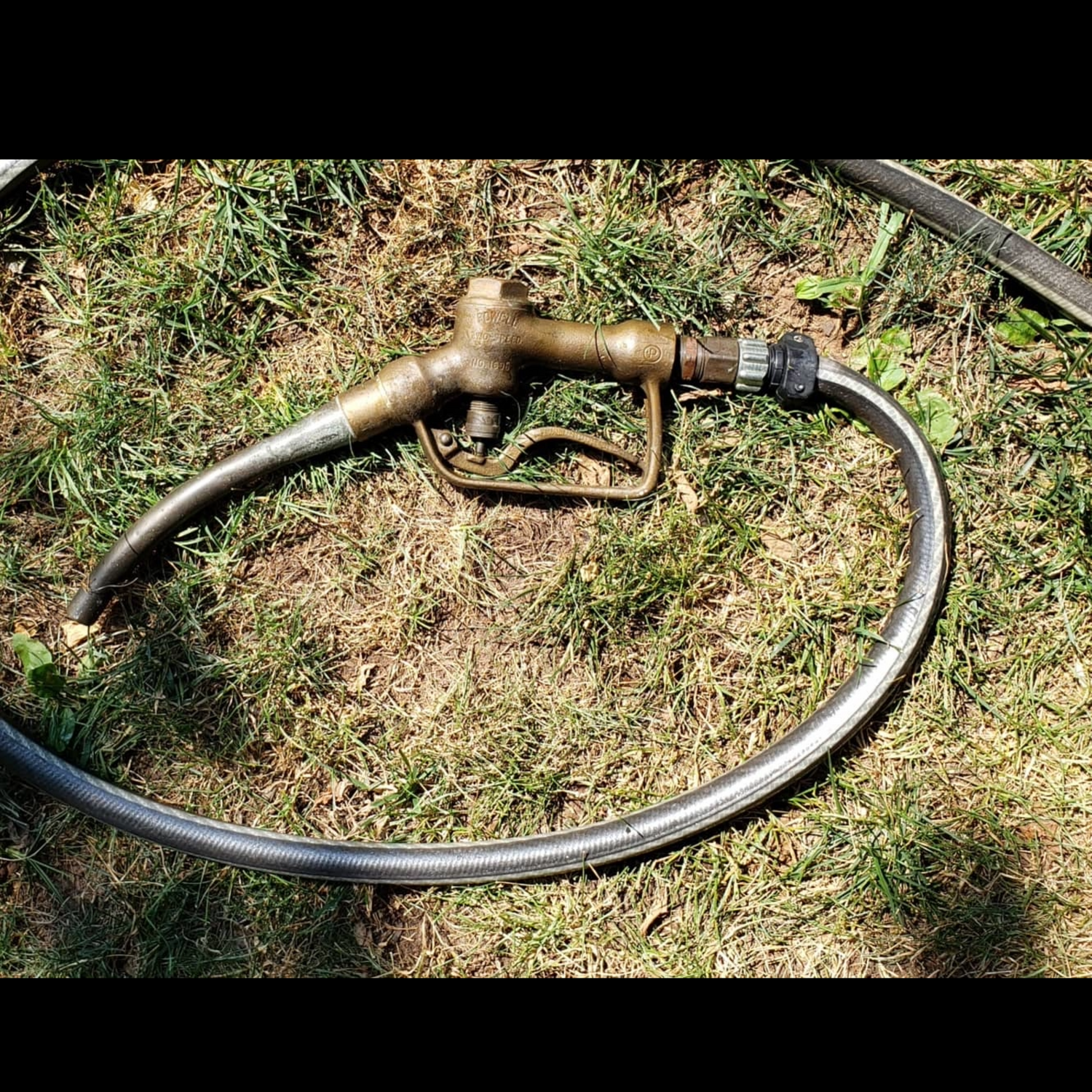 Vintage two-speed gas pump nozzle repurposed as a garden hose attachment. Upcycled auction find.