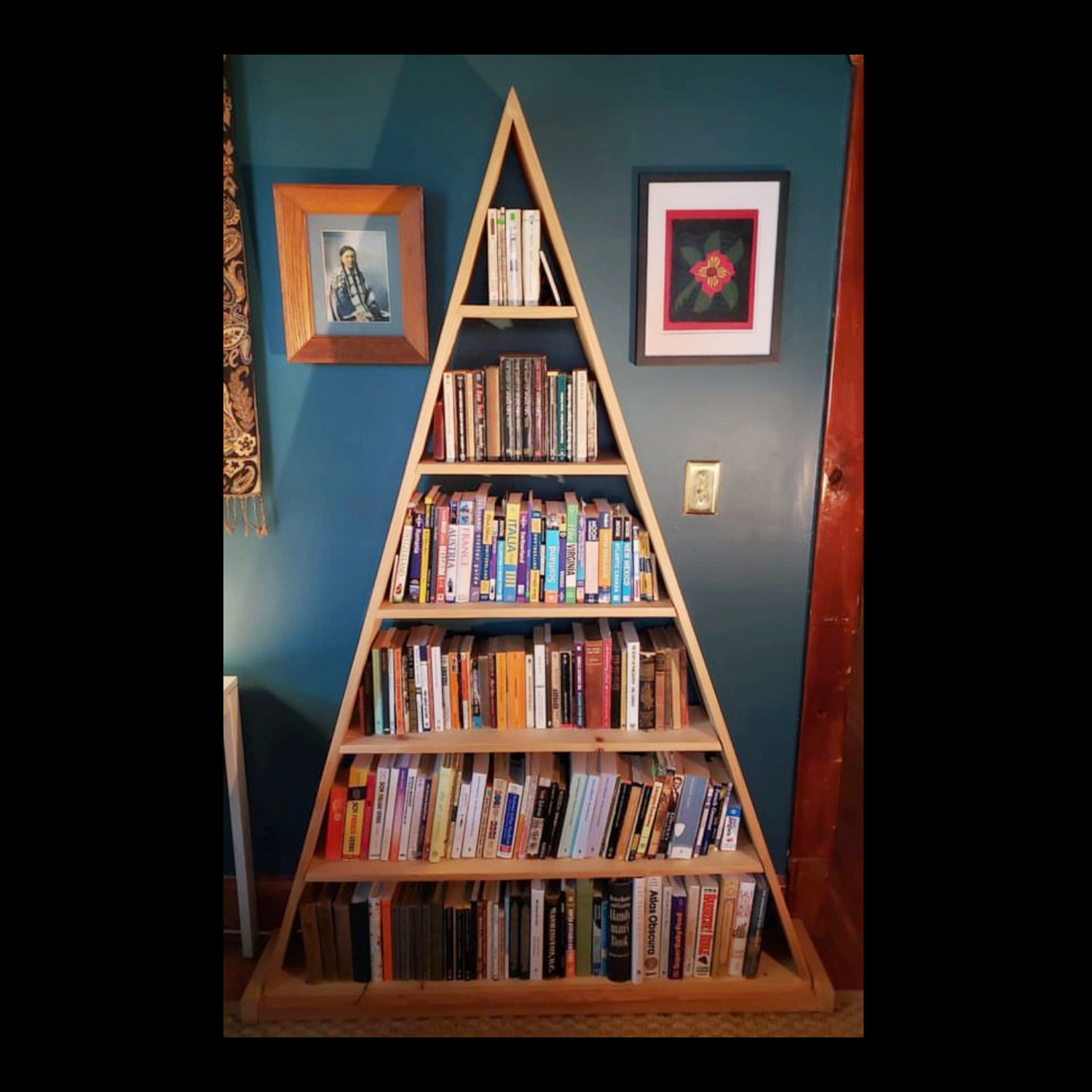 Six-foot-tall pyramid bookshelf by Fox & Thistle Studio, made for displaying vintage blue ball jars, also used for books.
