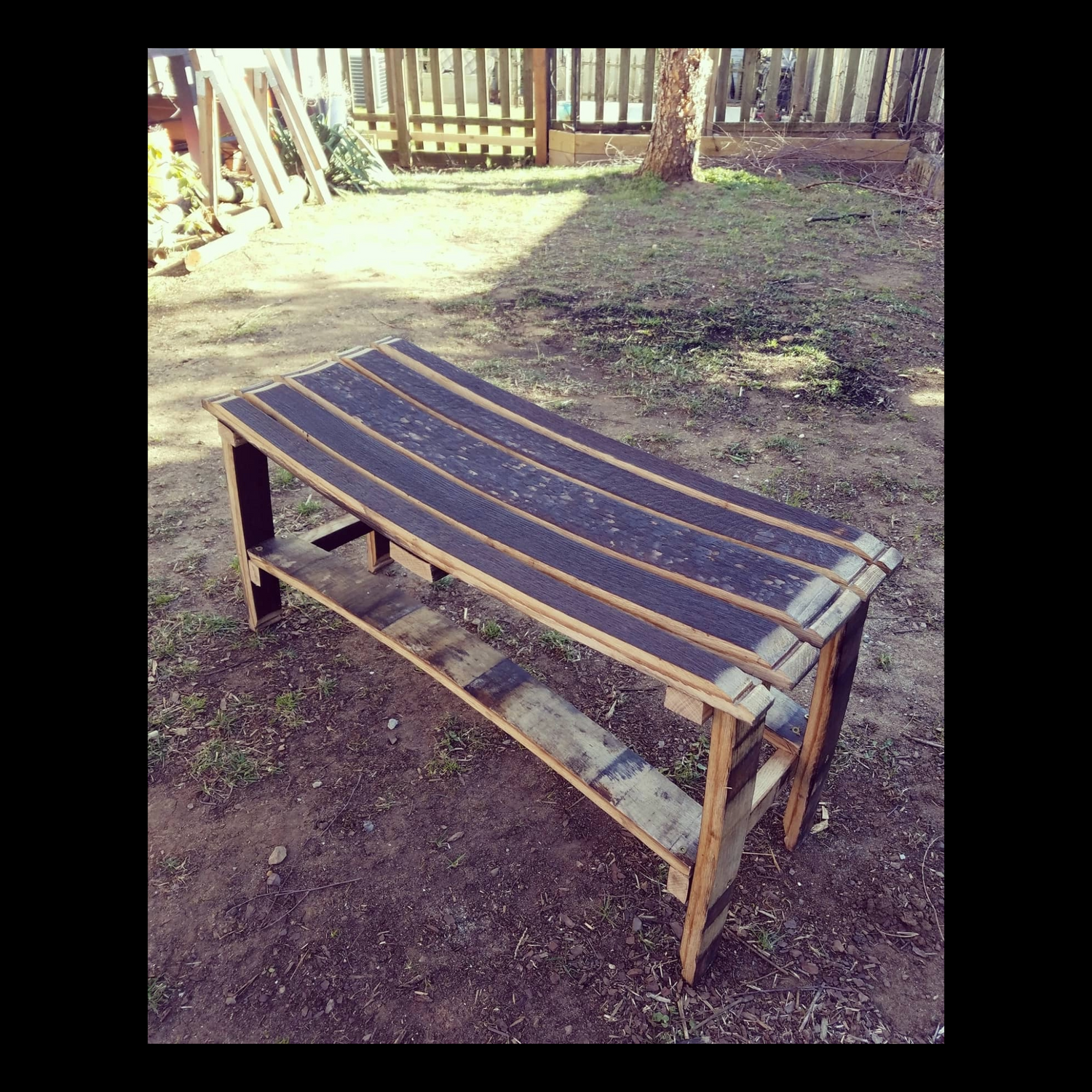 Two-seater bench made from reclaimed bourbon barrel staves with curved wooden slats.