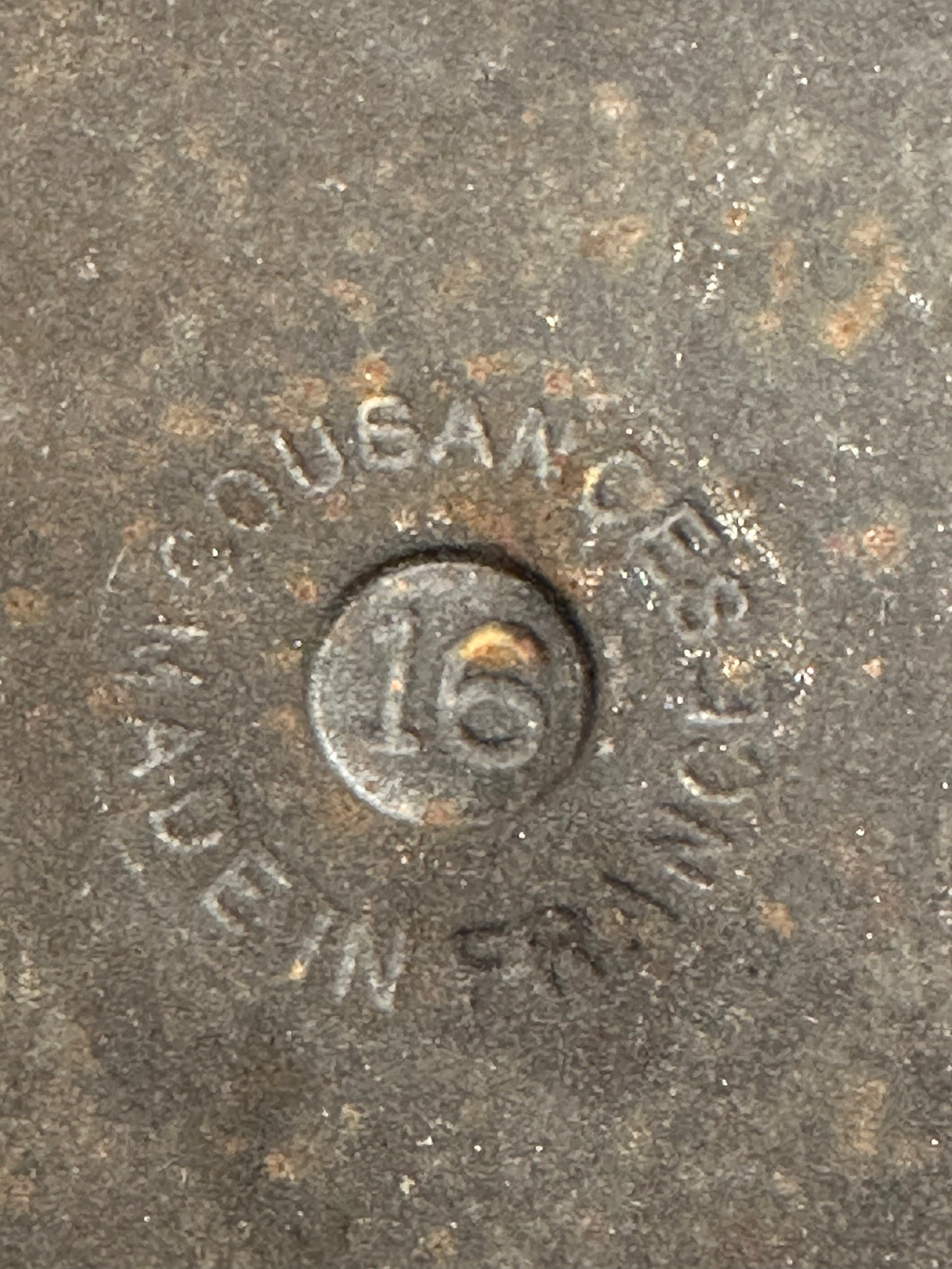 Metal object with 'MADE IN France' and number '16'  and ' Cousances' engraving on a textured surface.