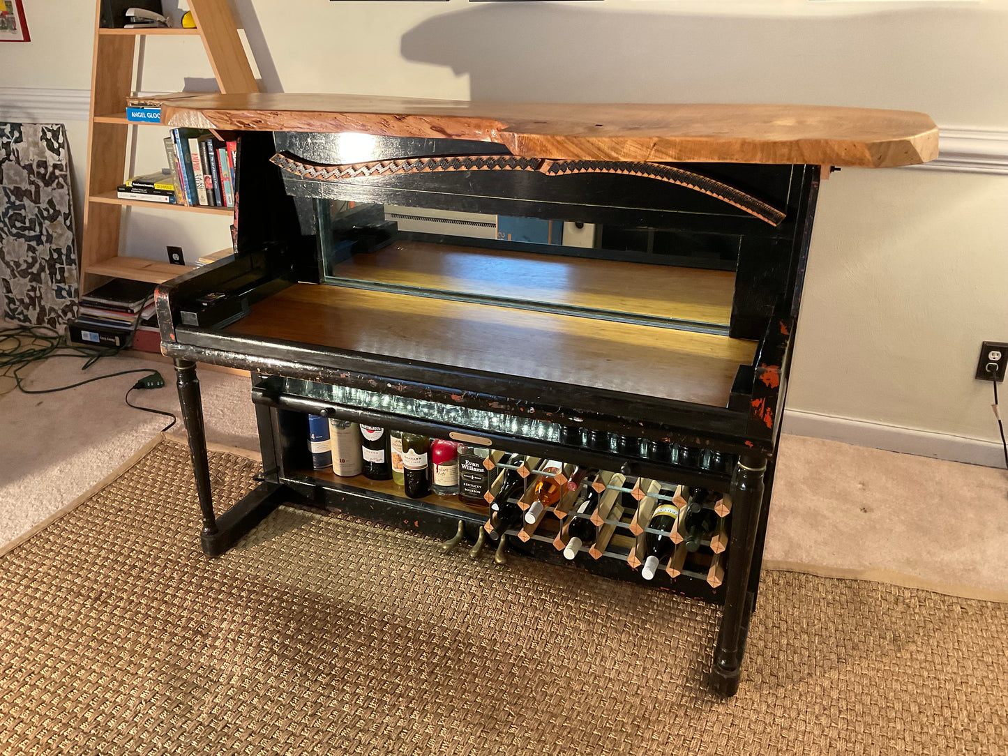 Wine rack with bottles on a wooden shelf in a room setting.