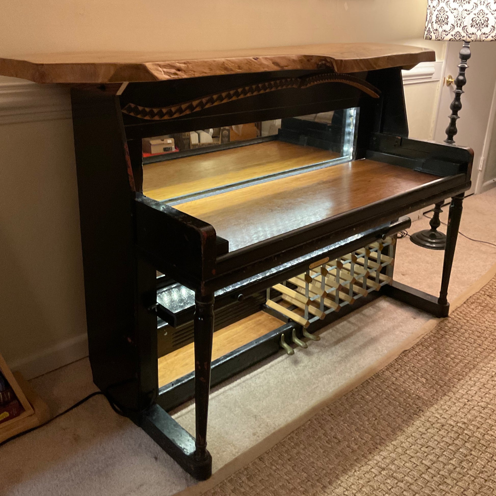 Wooden piano bench with a textured wooden top in a room setting.