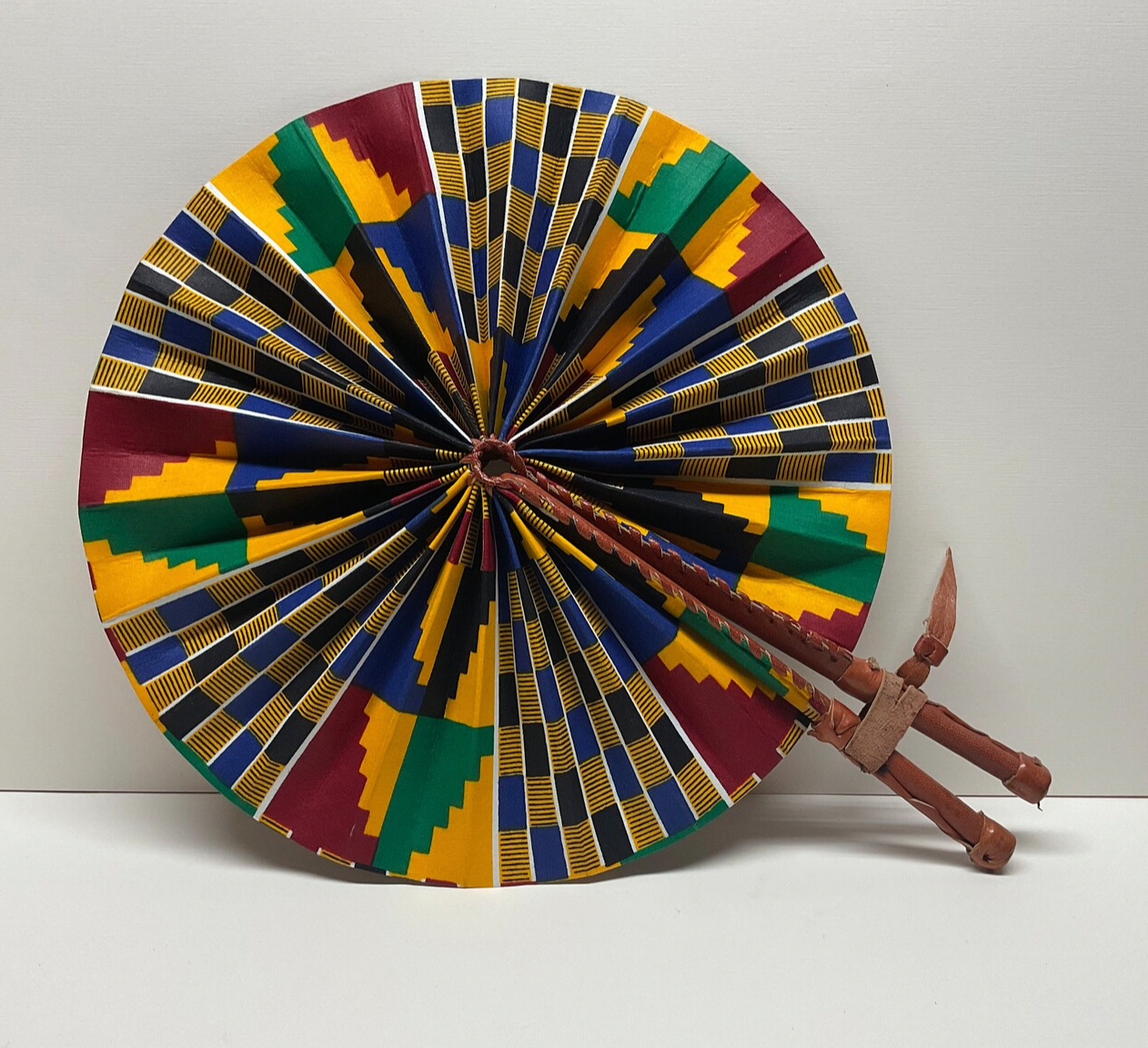 Colorful circular decorative fan with a leather base on a white background
