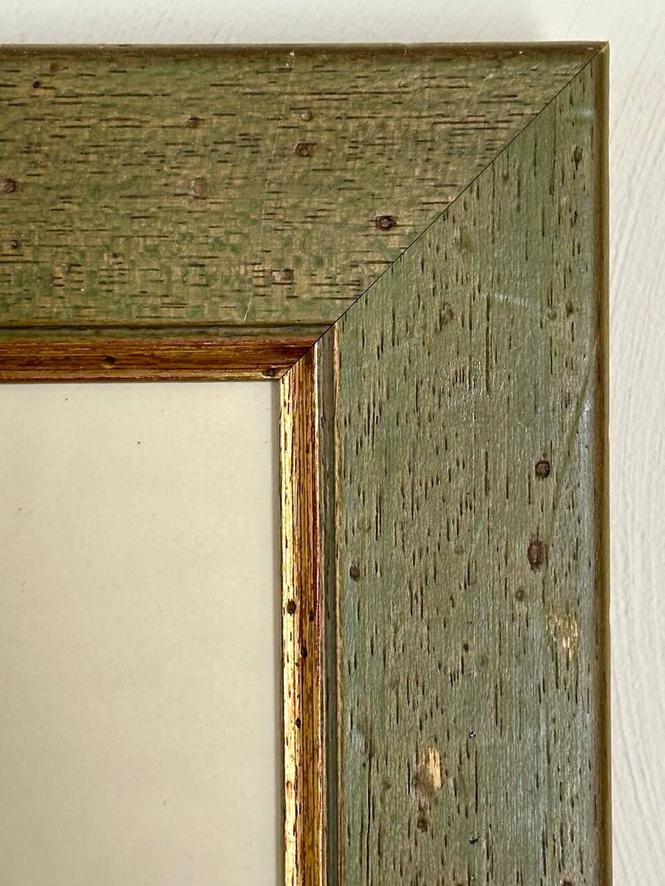 Close-up of a wooden green picture frame with a textured finish.