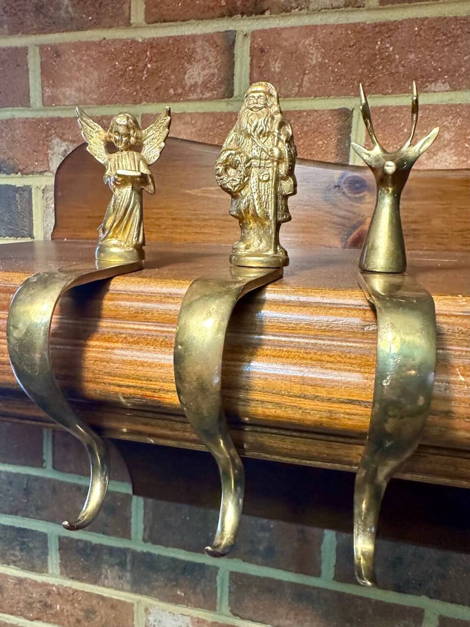 Three brass hooks on a mantel from a side view.