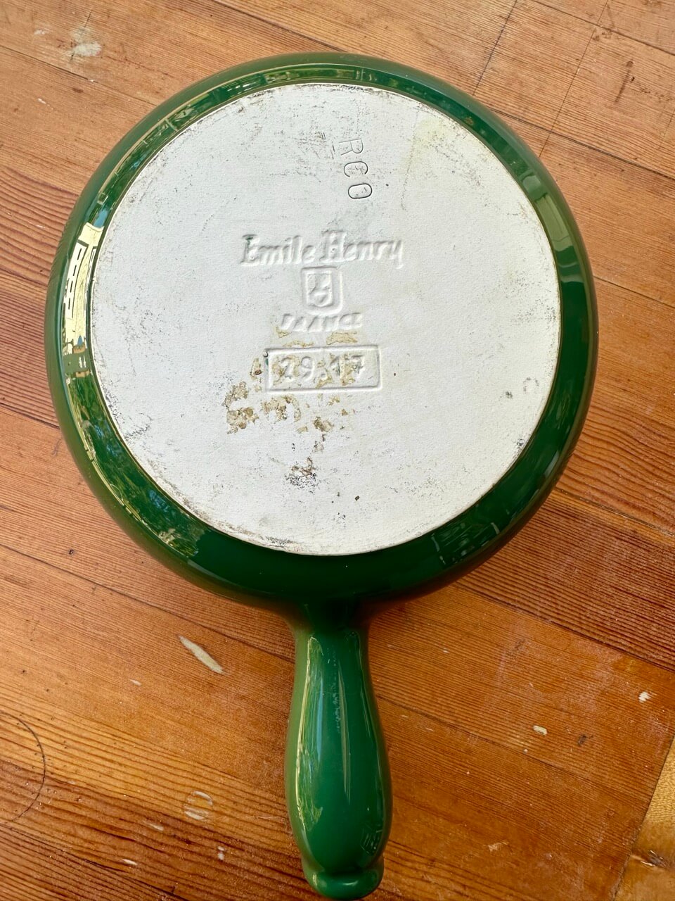 Green-handled fondue pot with 'Emile Henry' branding on a wooden surface