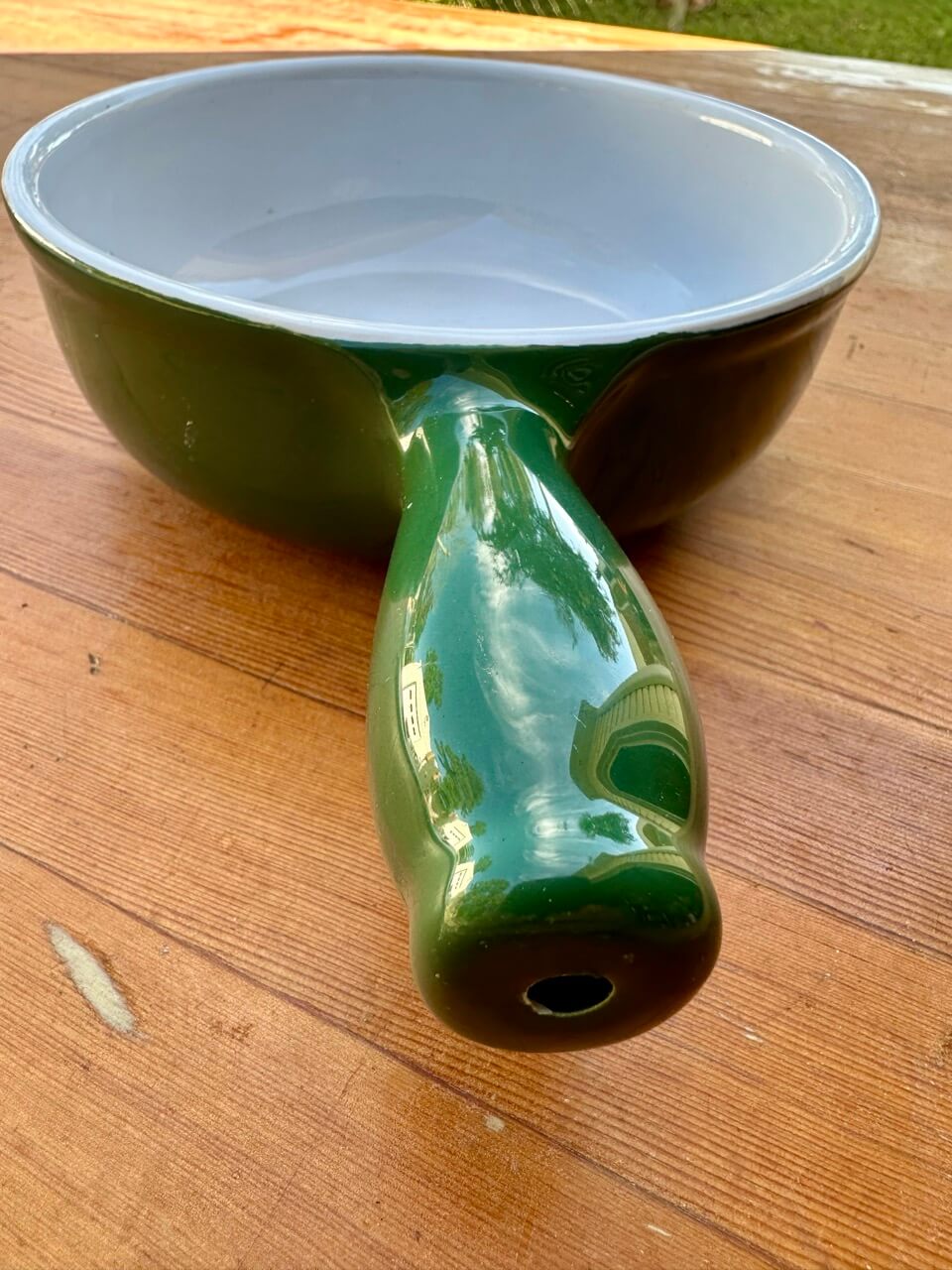 Green ceramic pot with a white interior on a wooden surface