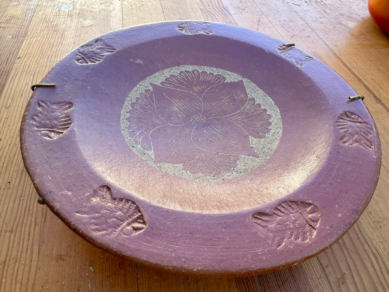 Red ceramic plate with fish patterns on a wooden surface