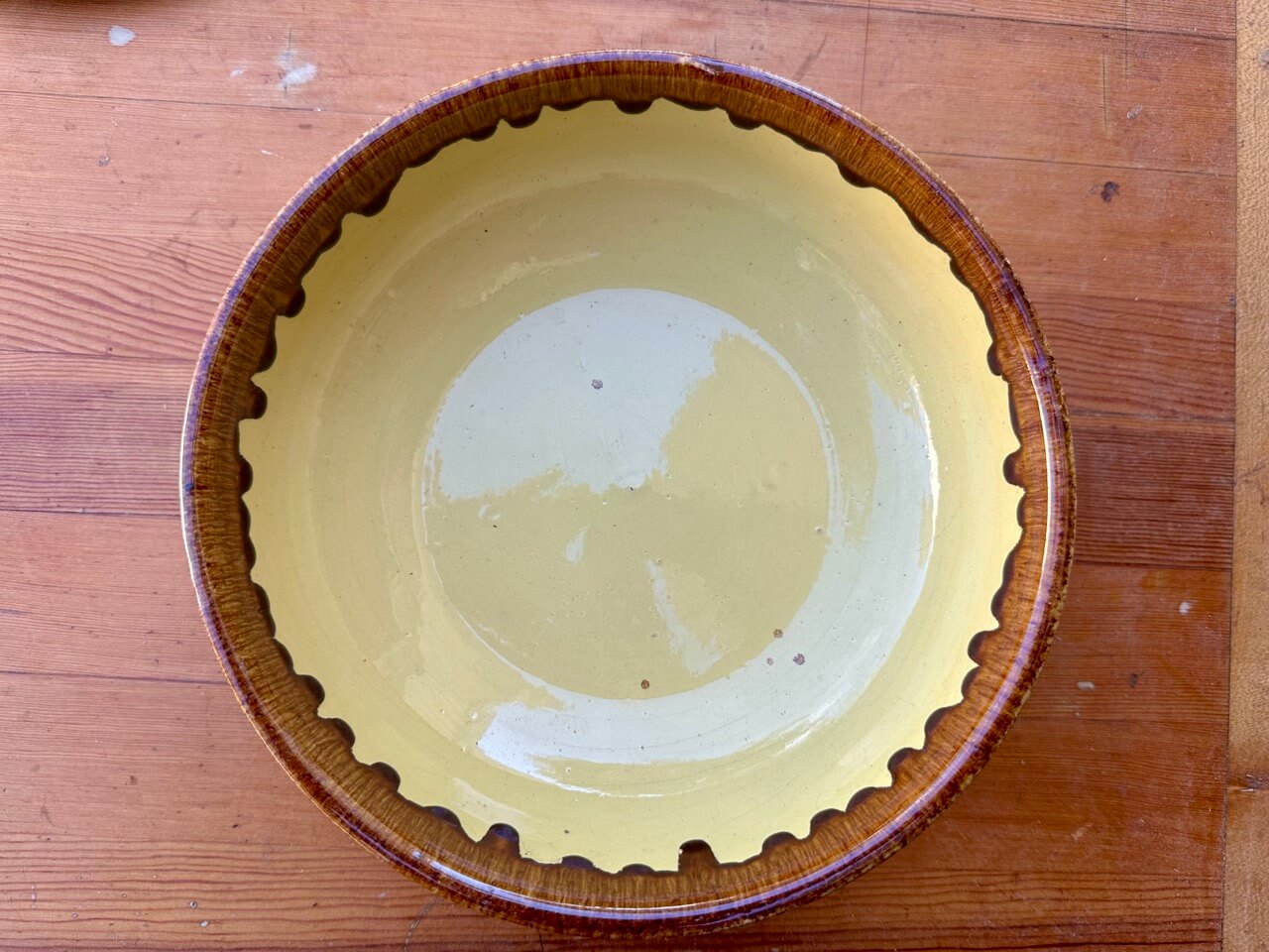 Ceramic pie dish with scalloped edge on a wooden surface
