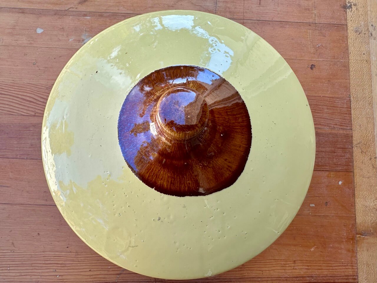 Round ceramic plate with a gradient from yellow to brown on a wooden surface