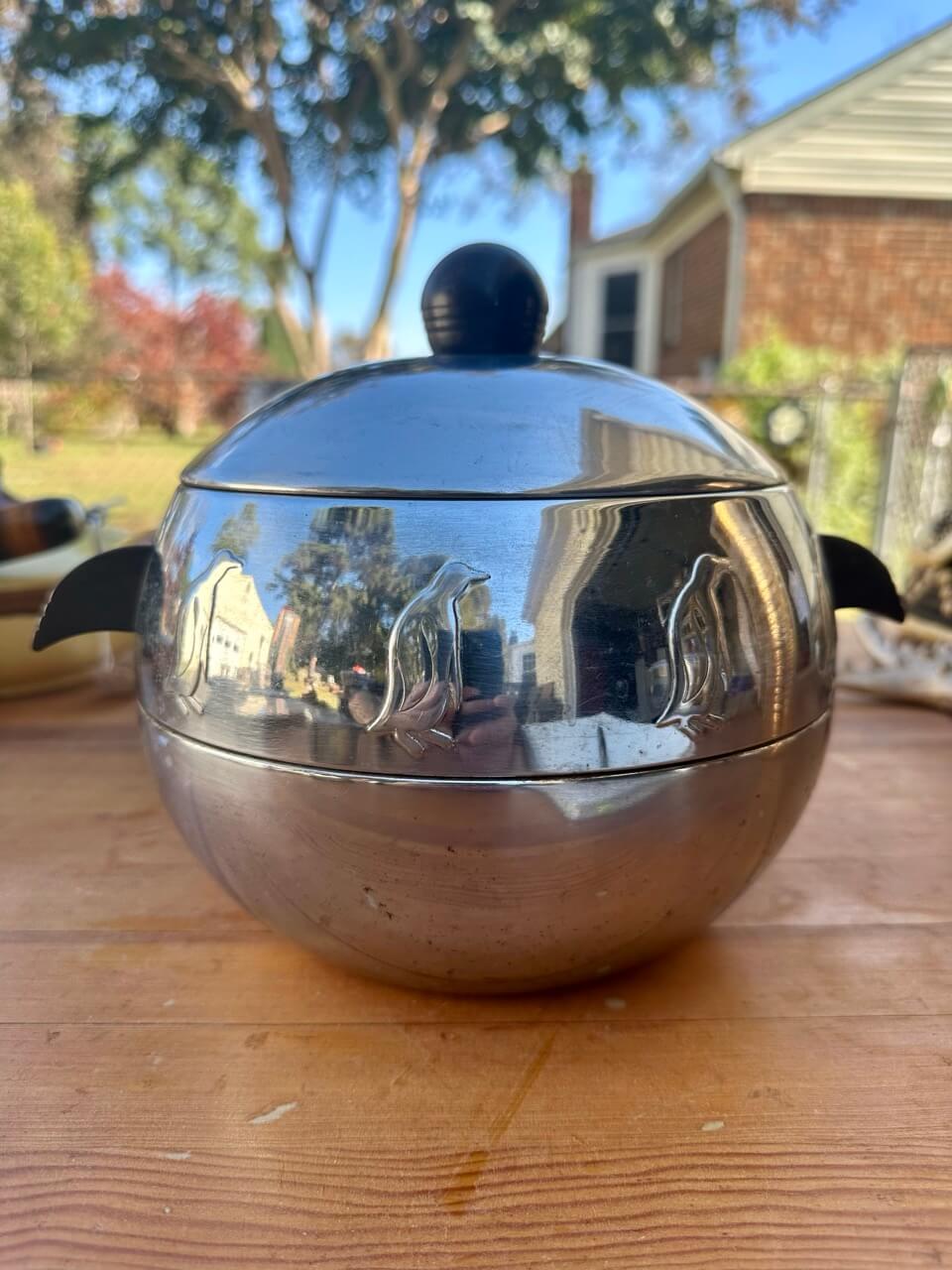 Metallic spherical object with a lid on a wooden surface outdoors