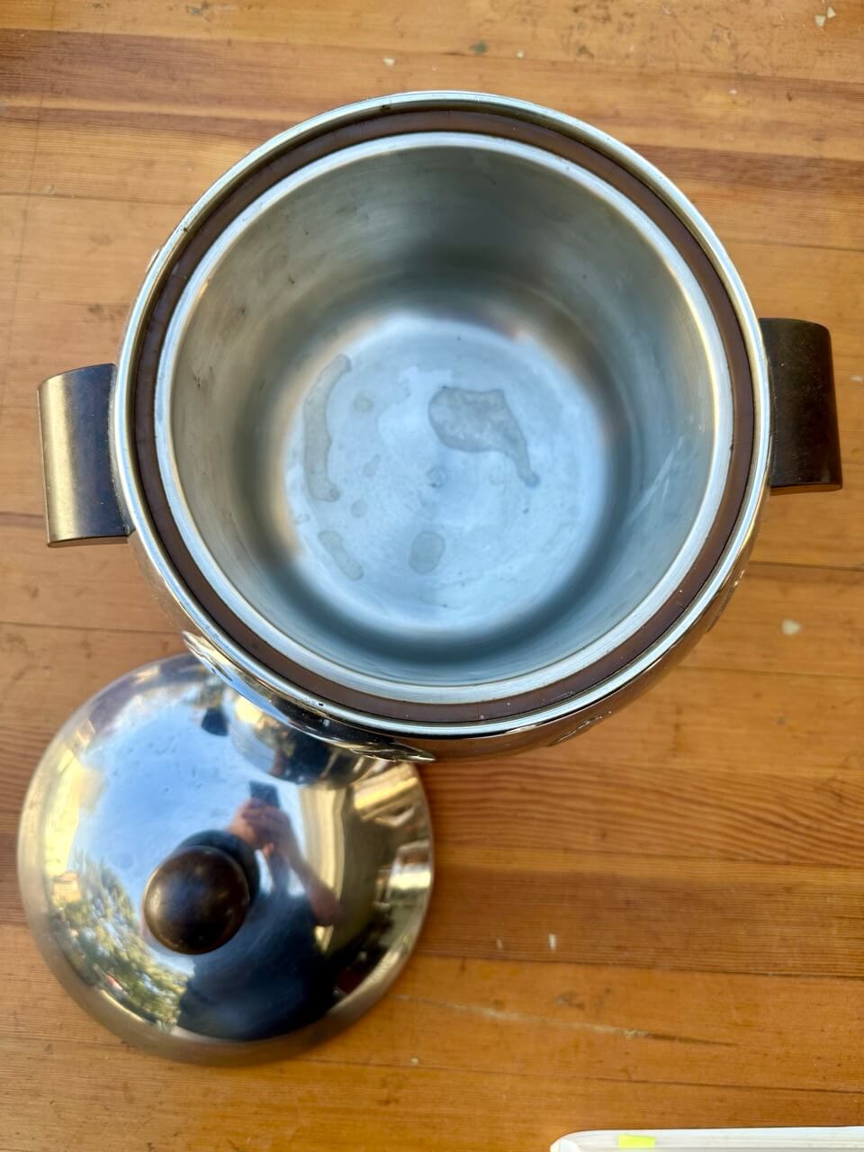 Stainless steel pot with lid on a wooden surface